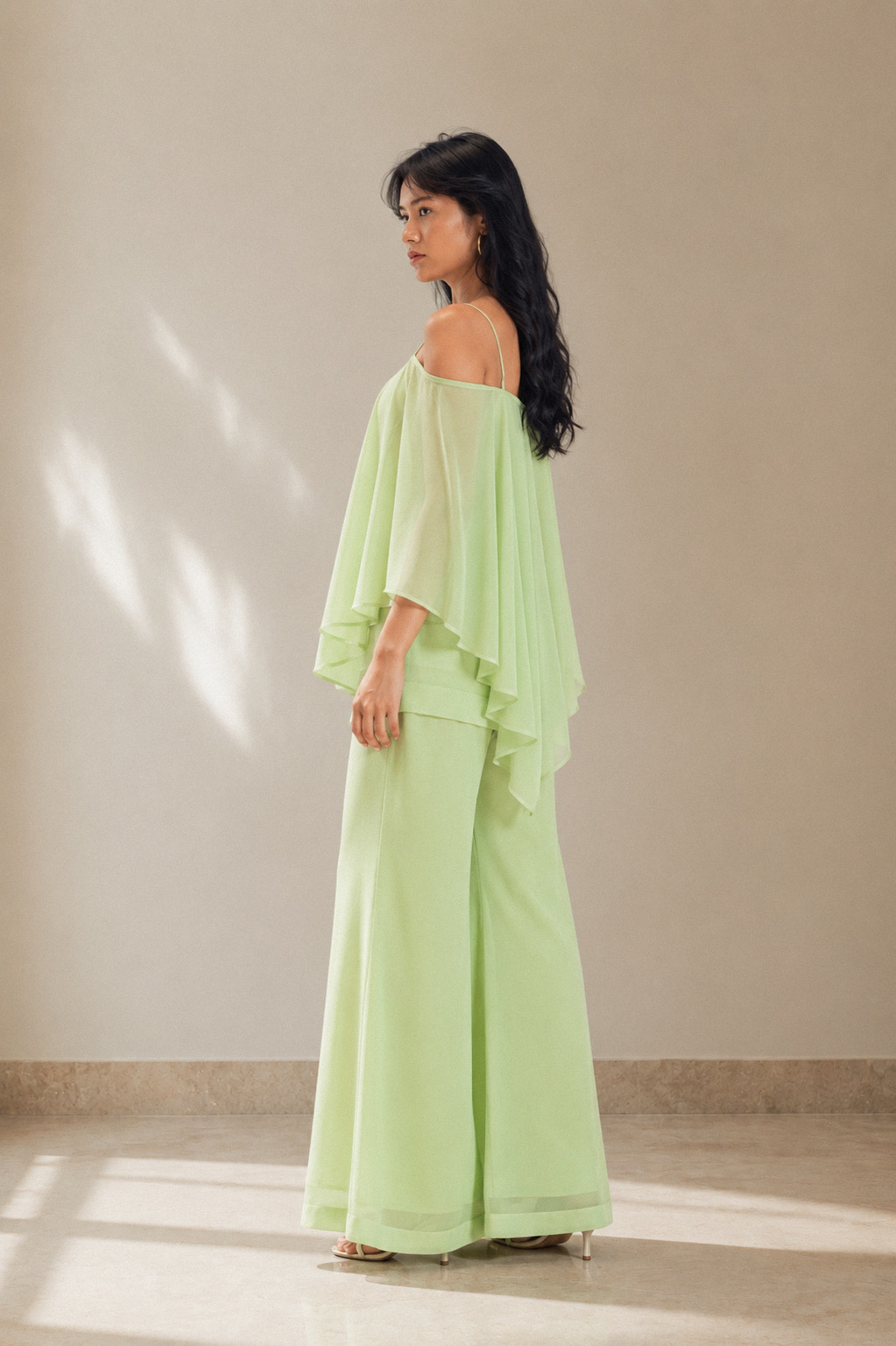 Side view of the pistachio green georgette cape kurti set showing the layered handkerchief cape hem and palazzo drape